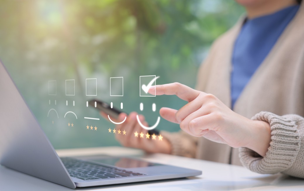 Customer review satisfaction feedback survey concept. Person interacts with laptop, giving a five-star rating using a digital feedback system, illustrating positive customer satisfaction and feedback.