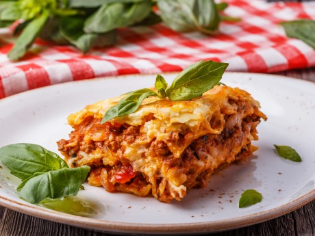 Traditional lasagna made with minced beef bolognese sauce and bechamel sauce topped with basil leafs.